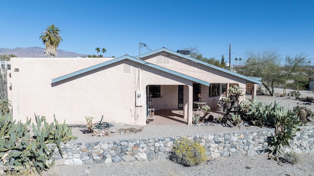 exterior space featuring cooling unit, a patio area, a mountain view, and stucco siding