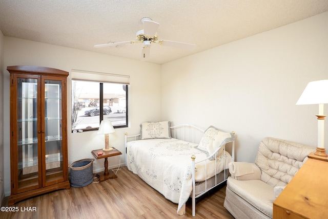 bedroom with a textured ceiling, wood finished floors, and a ceiling fan