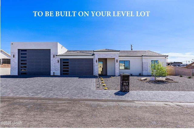 view of front of property with stucco siding, a tiled roof, decorative driveway, and a garage