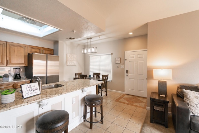 1650 Smoketree Ave S Unit 119, Lake Havasu City, AZ 86403 - kitchen with brown cabinets, light tile patterned floors, freestanding refrigerator, a breakfast bar, and recessed lighting
