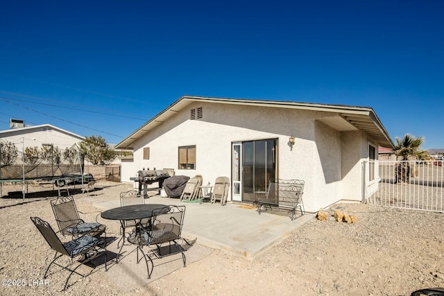 rear view of property featuring a patio area and a trampoline