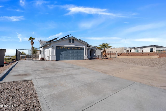 view of side of property with solar panels, an attached garage, fence, driveway, and a gate