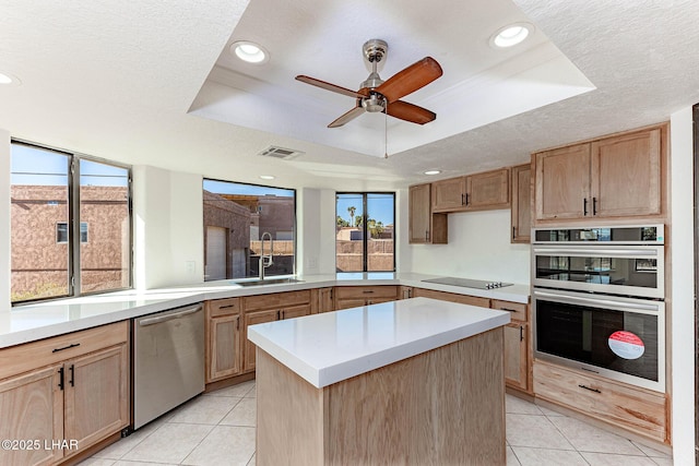 kitchen with light tile patterned flooring, sink, a tray ceiling, a kitchen island, and stainless steel appliances