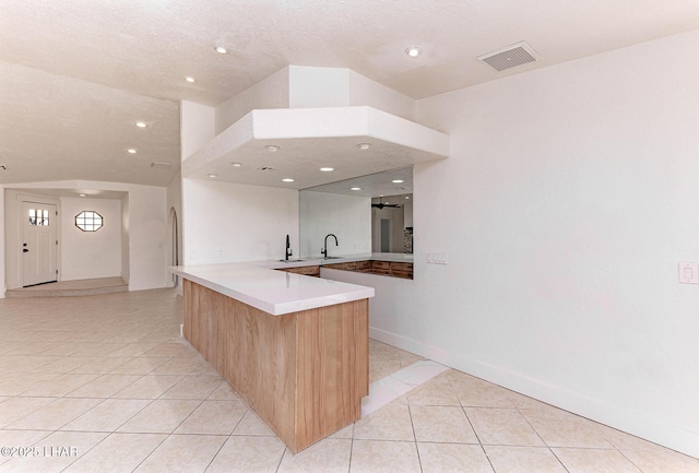 kitchen with kitchen peninsula, light brown cabinets, and light tile patterned floors