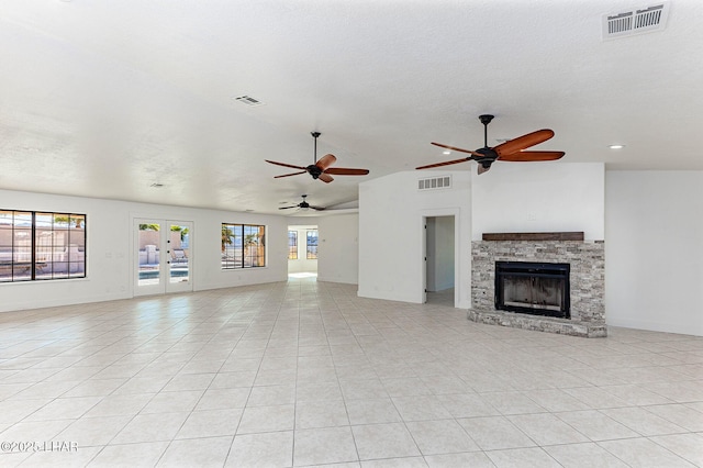 unfurnished living room with french doors, vaulted ceiling, a textured ceiling, light tile patterned floors, and a fireplace