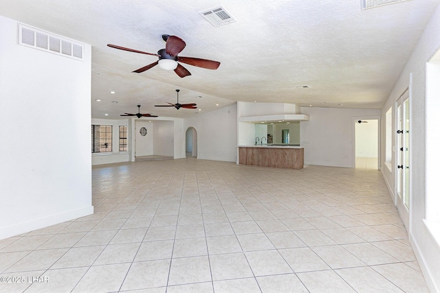 unfurnished living room featuring light tile patterned floors, sink, and a textured ceiling