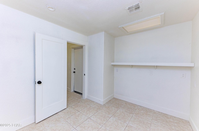 tiled spare room featuring a textured ceiling