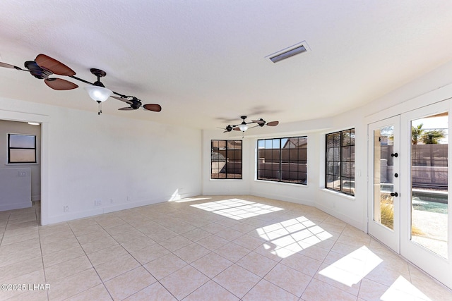 interior space featuring ceiling fan, french doors, a textured ceiling, and light tile patterned flooring