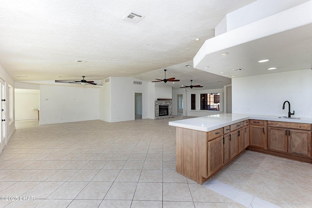 kitchen with sink, kitchen peninsula, ceiling fan, and light tile patterned flooring