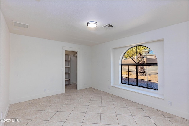 tiled spare room with a textured ceiling