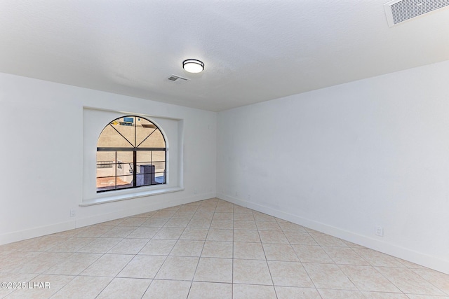 tiled empty room with a textured ceiling