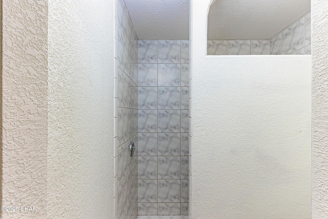 bathroom featuring a tile shower and a textured ceiling