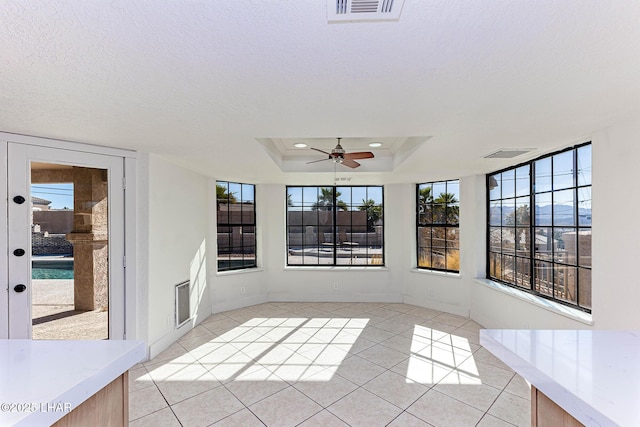 unfurnished sunroom with a raised ceiling and ceiling fan