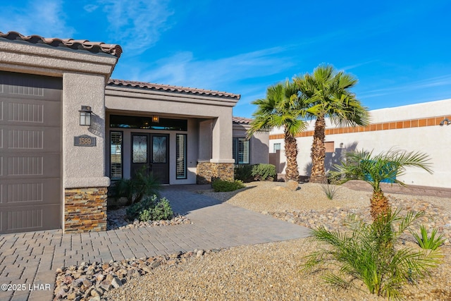 1589 Park Terrace Ave, Lake Havasu City, AZ 86404 - view of exterior entry featuring an attached garage, stone siding, a tiled roof, and stucco siding