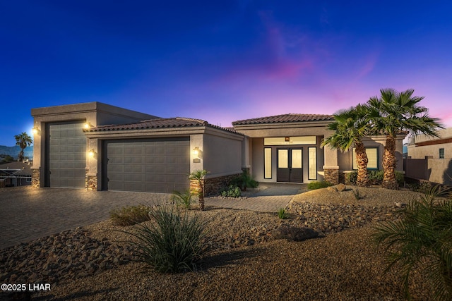 view of front of home featuring a garage, decorative driveway, a tile roof, and stucco siding