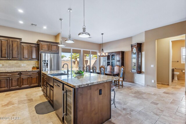 1589 Park Terrace Ave, Lake Havasu City, AZ 86404 - kitchen featuring light stone counters, a breakfast bar area, decorative backsplash, an island with sink, and decorative light fixtures