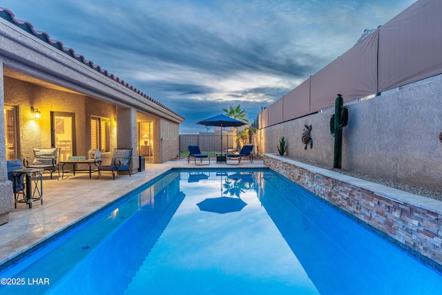 pool at dusk with a patio and outdoor lounge area