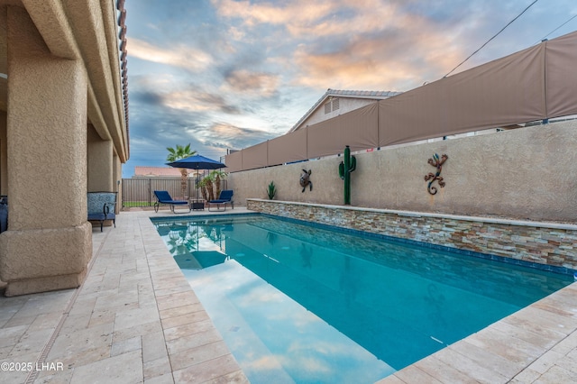 pool at dusk with a patio area