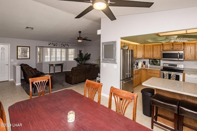 dining area featuring ceiling fan, vaulted ceiling, and light tile patterned floors