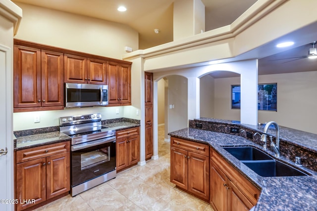 879 Window Rock Plz, Lake Havasu City, AZ 86406 - kitchen featuring appliances with stainless steel finishes, dark stone countertops, arched walkways, brown cabinetry, and recessed lighting