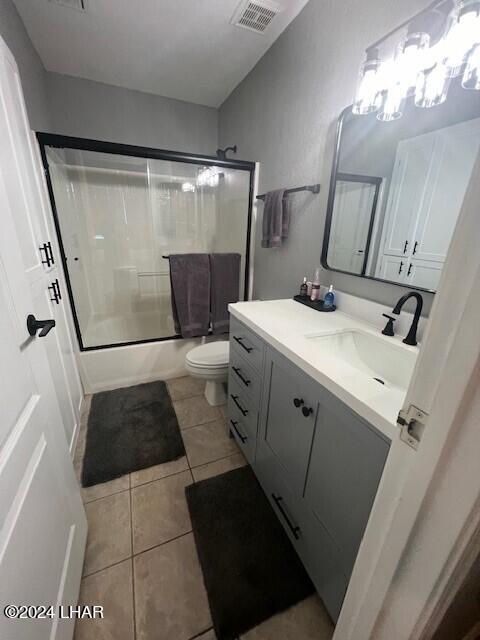 full bathroom featuring enclosed tub / shower combo, vanity, toilet, and tile patterned flooring