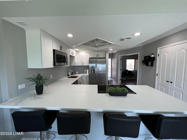 kitchen featuring sink, a breakfast bar, appliances with stainless steel finishes, white cabinetry, and kitchen peninsula