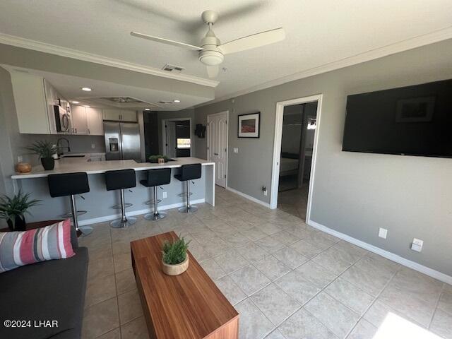 tiled living room featuring ceiling fan, ornamental molding, and sink