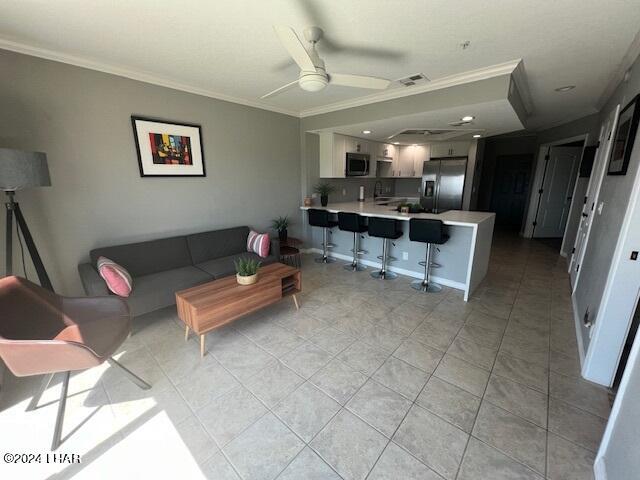 tiled living room with ceiling fan and ornamental molding