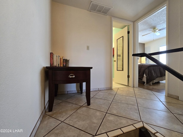 hallway with a textured ceiling and light tile patterned floors