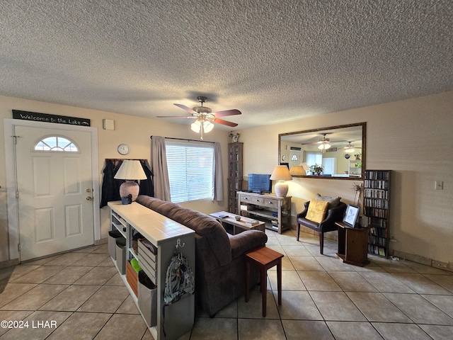 living room with light tile patterned flooring, ceiling fan, and a textured ceiling