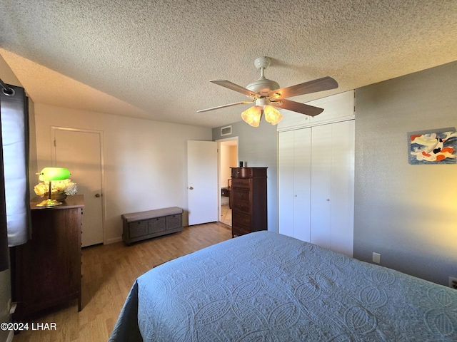 bedroom with ceiling fan, a textured ceiling, light hardwood / wood-style floors, and a closet