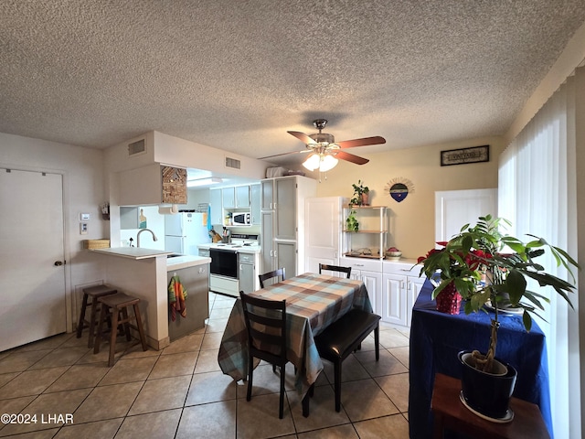 dining area featuring a textured ceiling, ceiling fan, and light tile patterned flooring