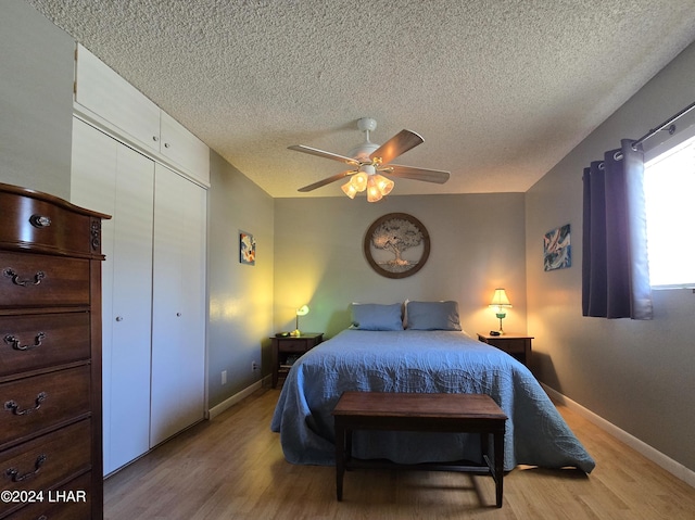 bedroom with ceiling fan, a textured ceiling, light wood-type flooring, and a closet