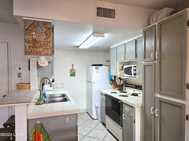 kitchen featuring light tile patterned flooring, a breakfast bar, sink, kitchen peninsula, and white appliances