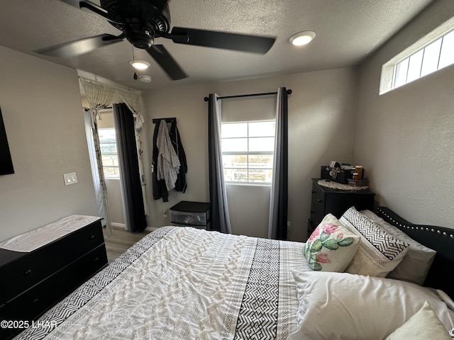 bedroom featuring a textured ceiling, ceiling fan, and multiple windows