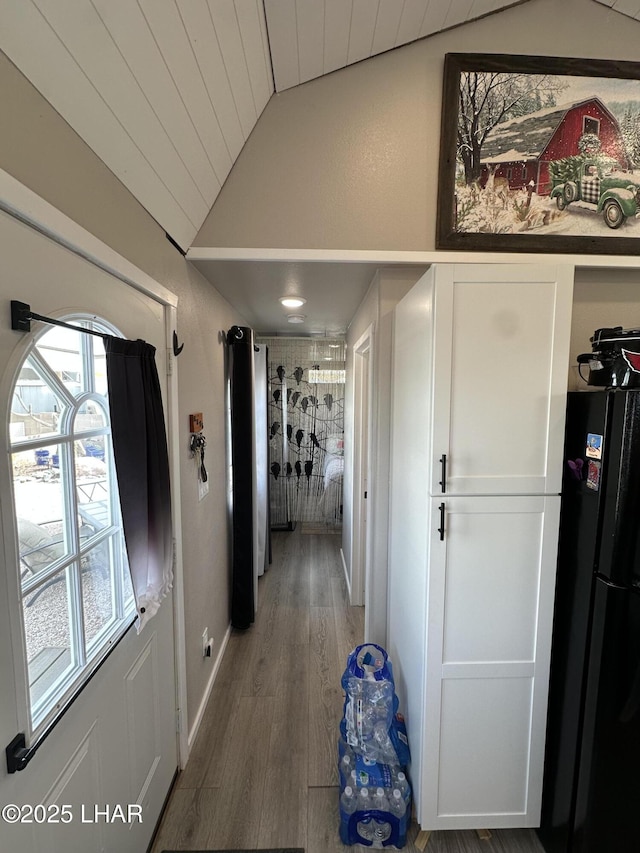 hall with vaulted ceiling and wood finished floors