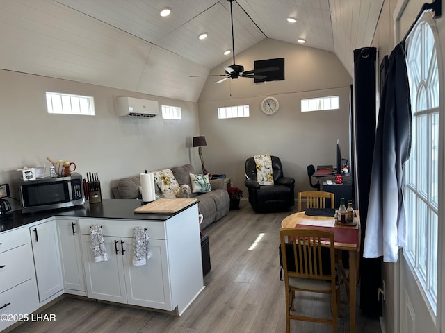 kitchen with light wood-style flooring, stainless steel microwave, open floor plan, and a wall mounted AC