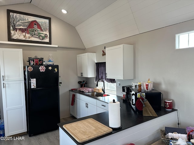 kitchen with light wood-style floors, freestanding refrigerator, white cabinetry, vaulted ceiling, and a sink