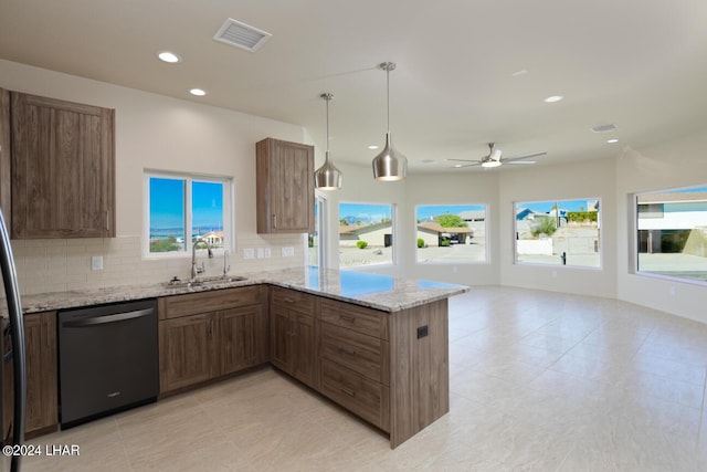 kitchen with pendant lighting, sink, dishwasher, light stone countertops, and kitchen peninsula