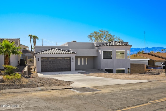 view of front of property featuring a garage, a mountain view, and central AC