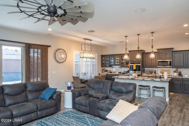 living room with sink, wood-type flooring, ceiling fan, and plenty of natural light