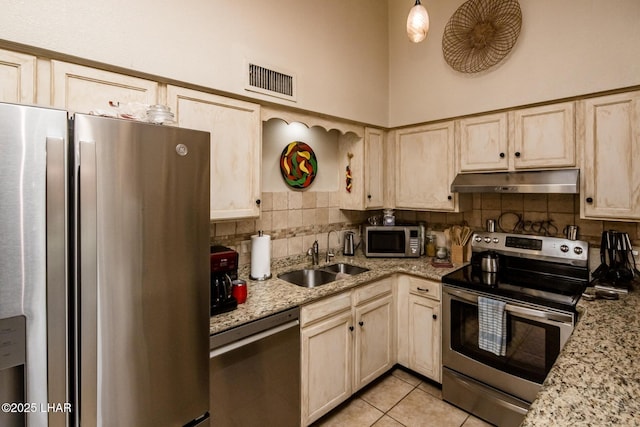 kitchen featuring tasteful backsplash, visible vents, under cabinet range hood, stainless steel appliances, and a sink