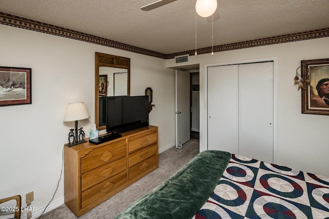 bedroom featuring visible vents, ceiling fan, light carpet, a closet, and a textured ceiling