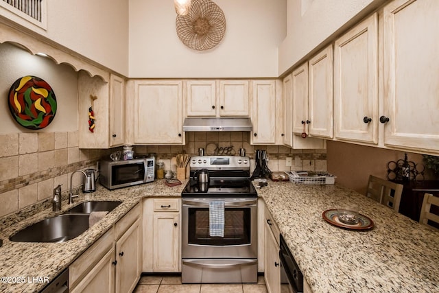 kitchen with under cabinet range hood, stainless steel appliances, decorative backsplash, and a sink