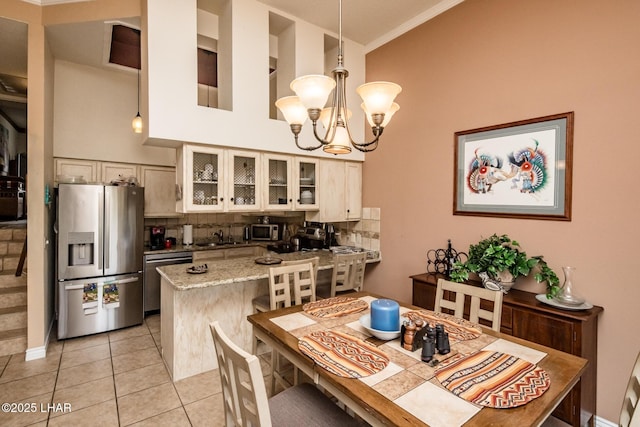 kitchen with backsplash, appliances with stainless steel finishes, a peninsula, an inviting chandelier, and light tile patterned floors