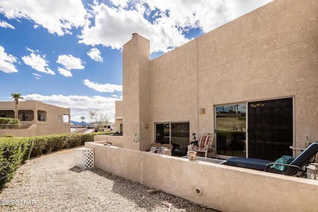 back of property featuring a chimney and stucco siding