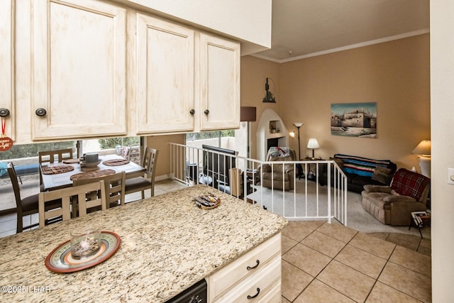 kitchen with light tile patterned flooring, open floor plan, light stone counters, and ornamental molding