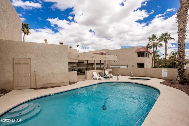 pool with a patio area and a hot tub