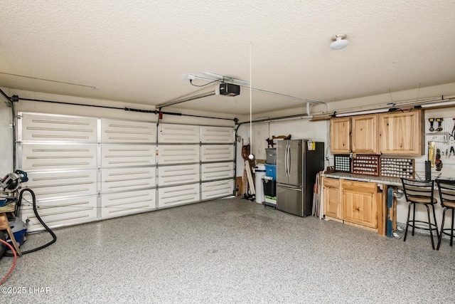 garage with a garage door opener and freestanding refrigerator