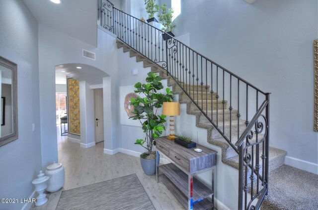 8551 River View Villas Dr Unit 15, Parker, AZ 85344 - staircase featuring arched walkways, a towering ceiling, baseboards, and wood finished floors